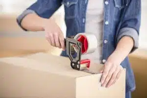 Montrose woman using a tape gun to secure valuables in a moving box to store