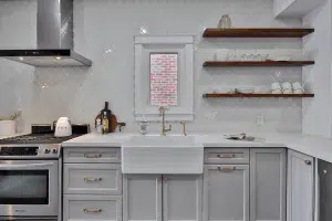 A white kitchen with brown wood shelves holding plates and mugs.