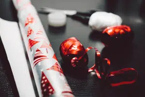 White wrapping paper and red ribbon on a grey table, ready for holiday decor storage.