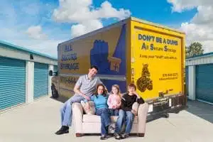 family sitting on sofa in front of the moving truck rental